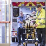 Trauma services providers wheel a patient on a stretcher into an emergency room