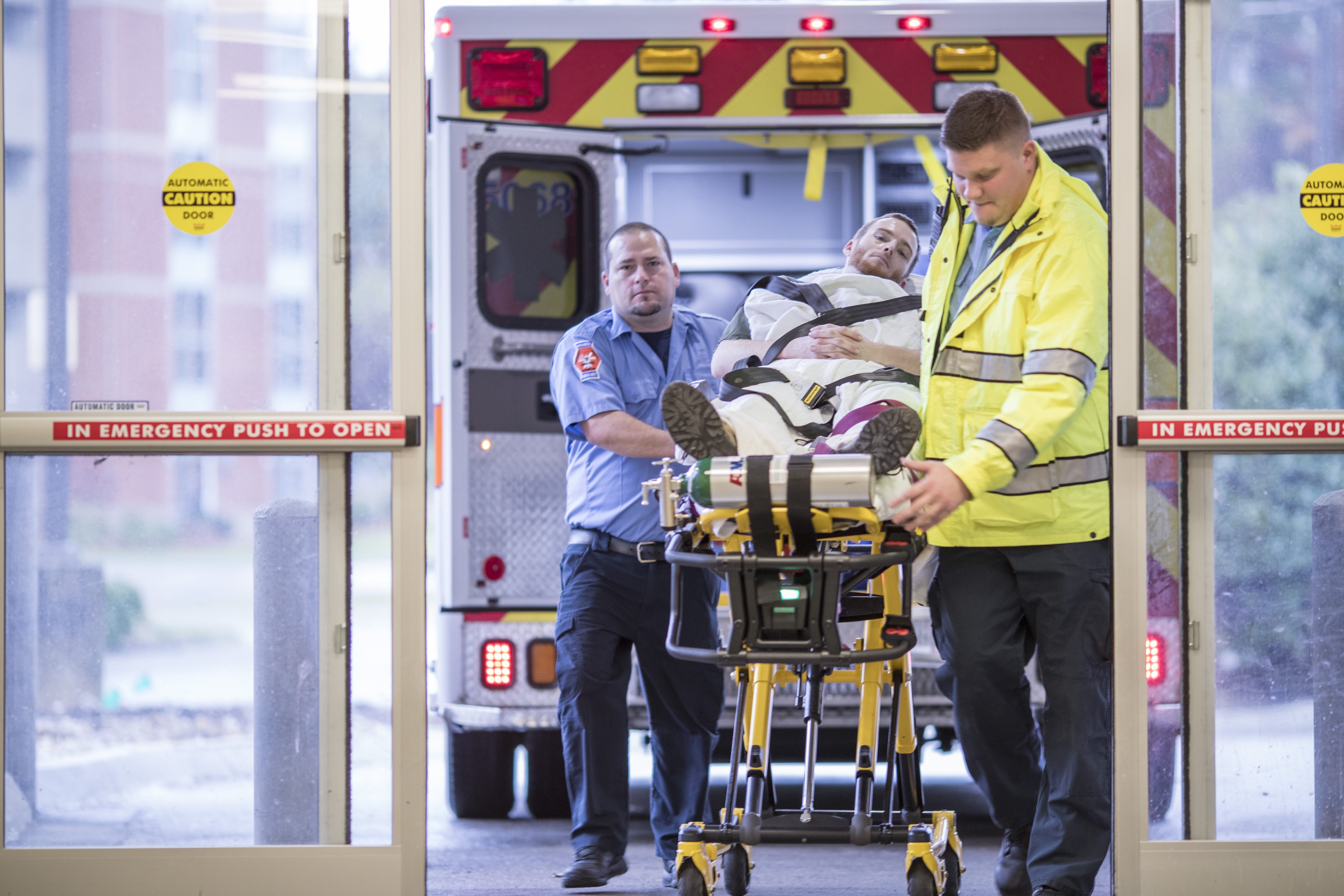 Trauma services providers wheel a patient on a stretcher into an emergency room