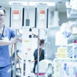 An RN pushes an IV cart through a hospital hallway