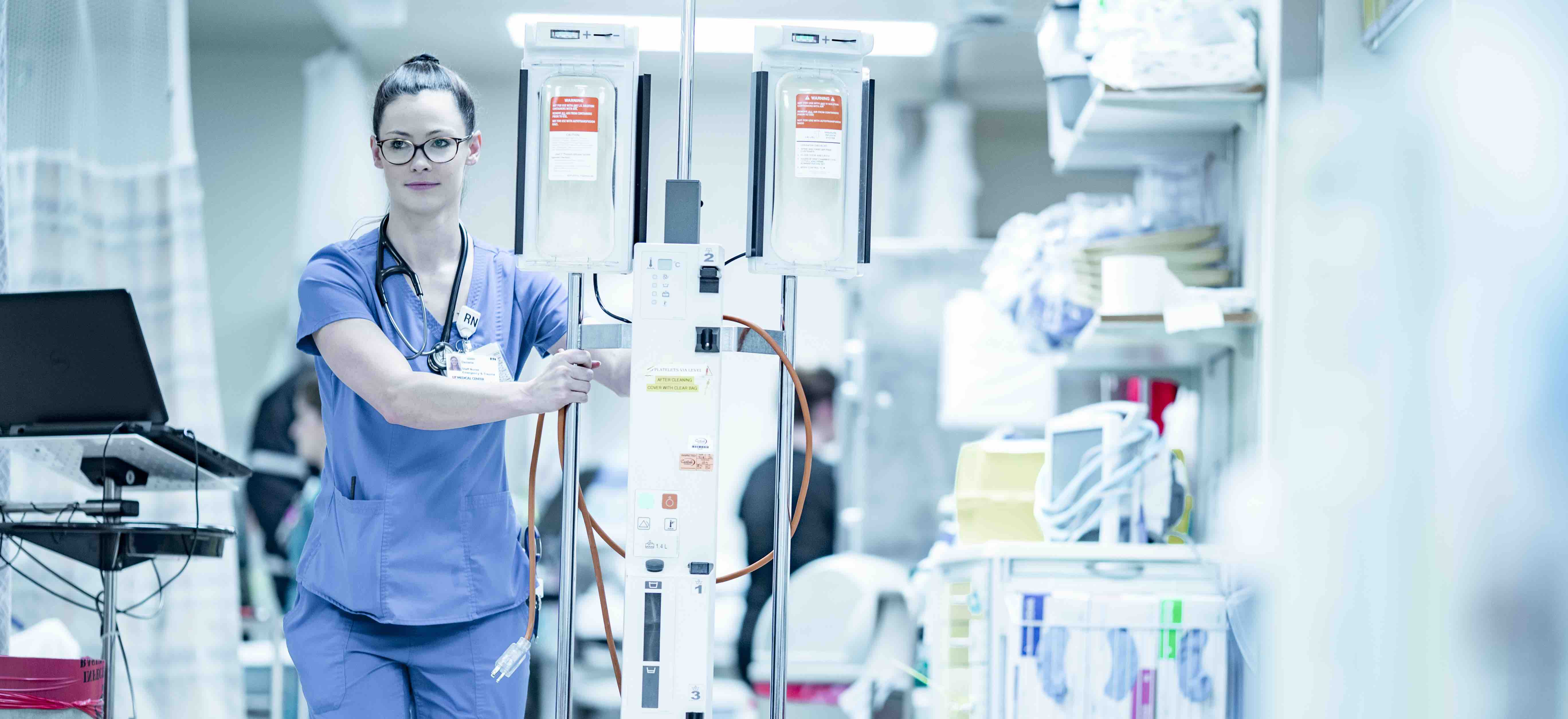 An RN pushes an IV cart through a hospital hallway