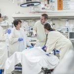 Emergency department physicians and providers work on a patient in an emergency room