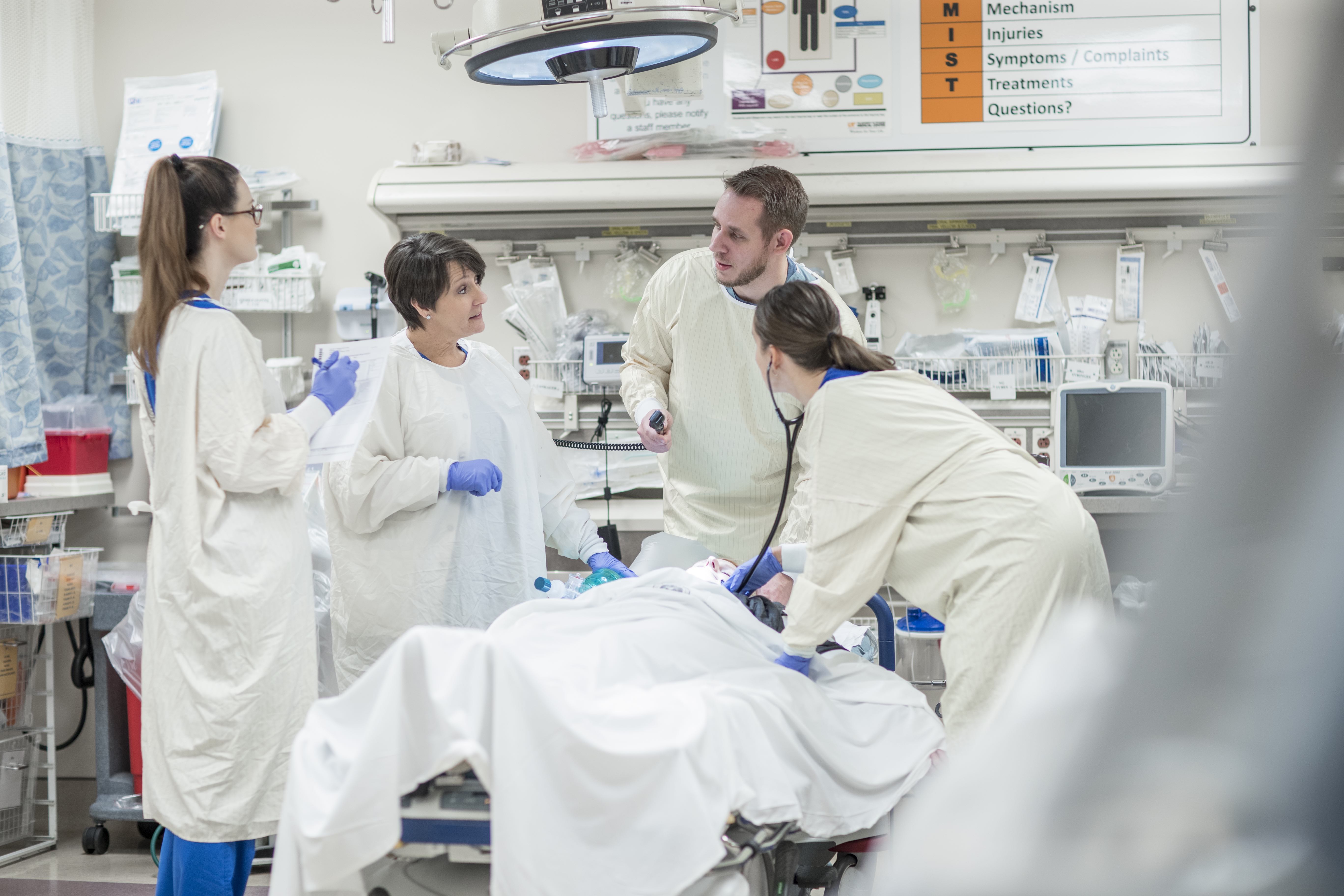 Emergency department physicians and providers work on a patient in an emergency room