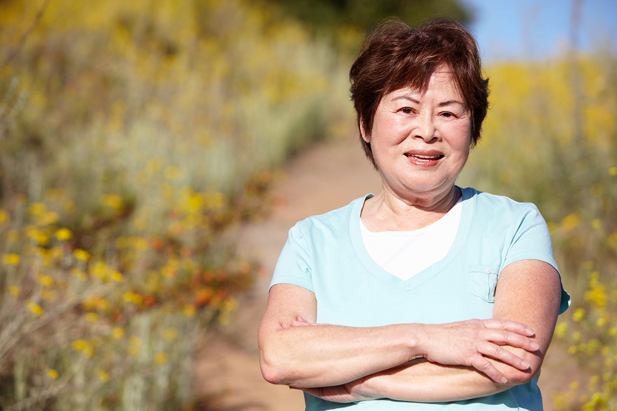 Senior Asian woman walking outdoors on a path