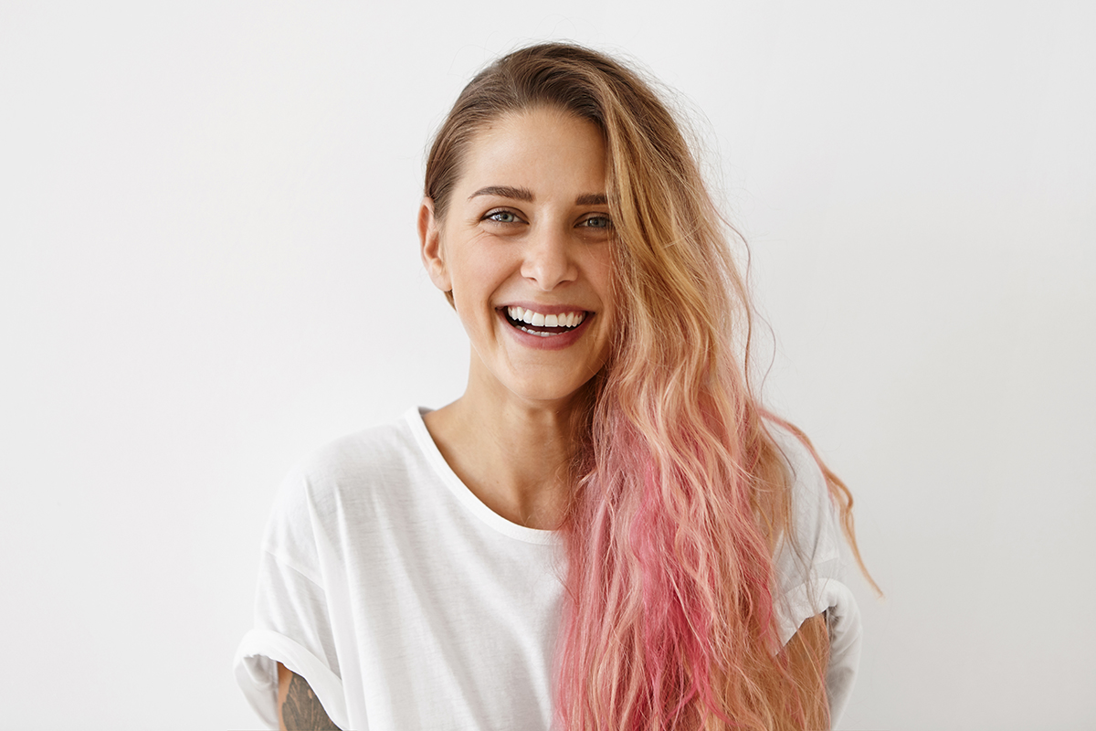 A smiling young woman with pink hair