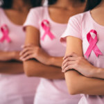 Cropped image of group of young multiracial woman with pink ribbons are struggling against breast cancer. Breast cancer and mammogram awareness