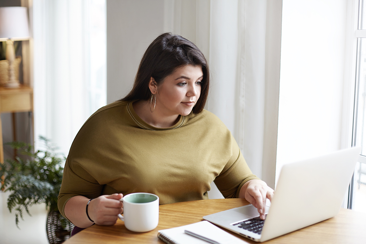 A Latina woman uses her laptop at the kitchen table