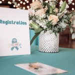 An event registration table with a teal tablecloth representing gynecologic cancer awareness