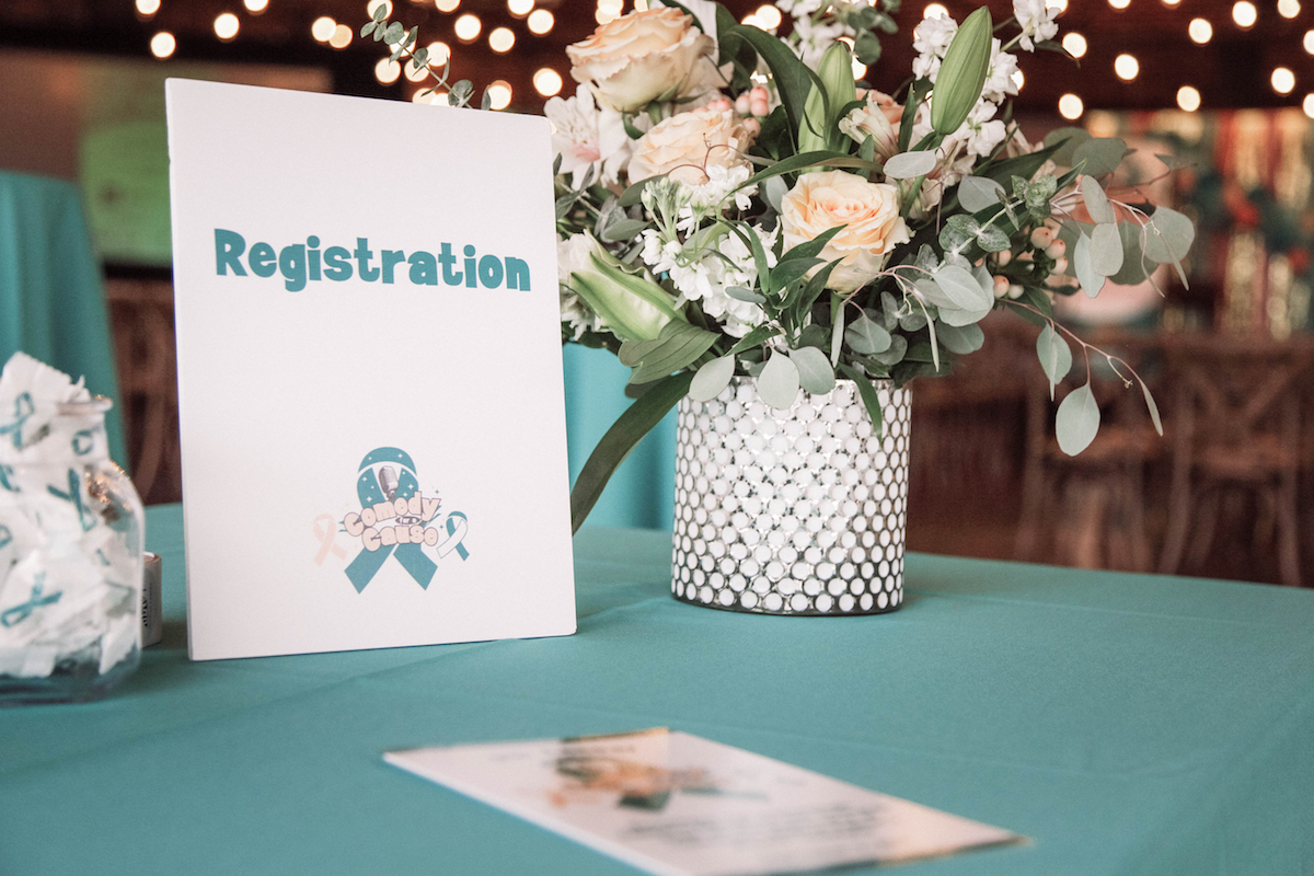 An event registration table with a teal tablecloth representing gynecologic cancer awareness