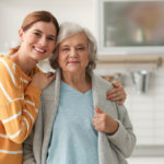 Elderly woman with female caregiver in kitchen.