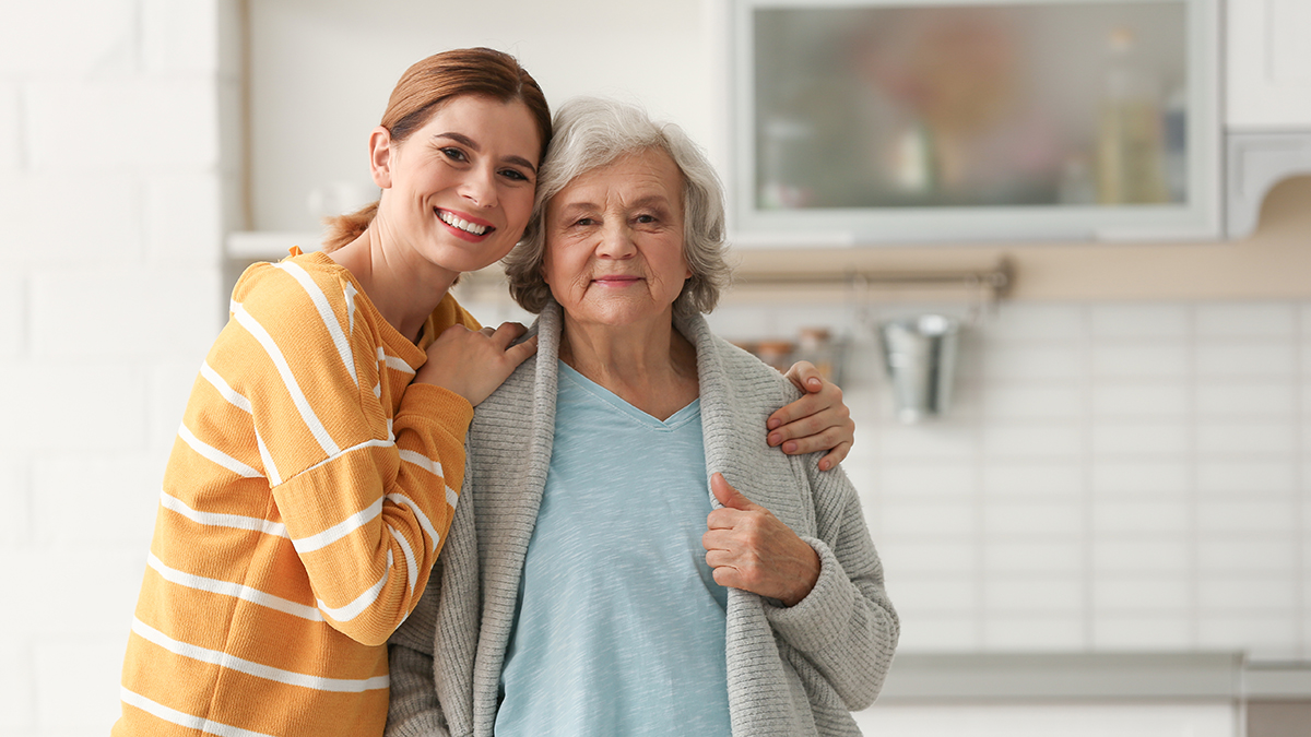 Elderly woman with female caregiver in kitchen.